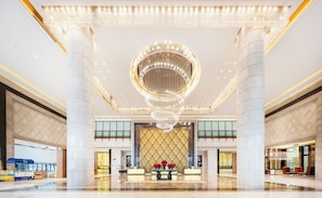 A spacious lobby with a grand chandelier, marble columns, and a reception desk with a floral arrangement. - Wanda Realm Langfang (Langfang)