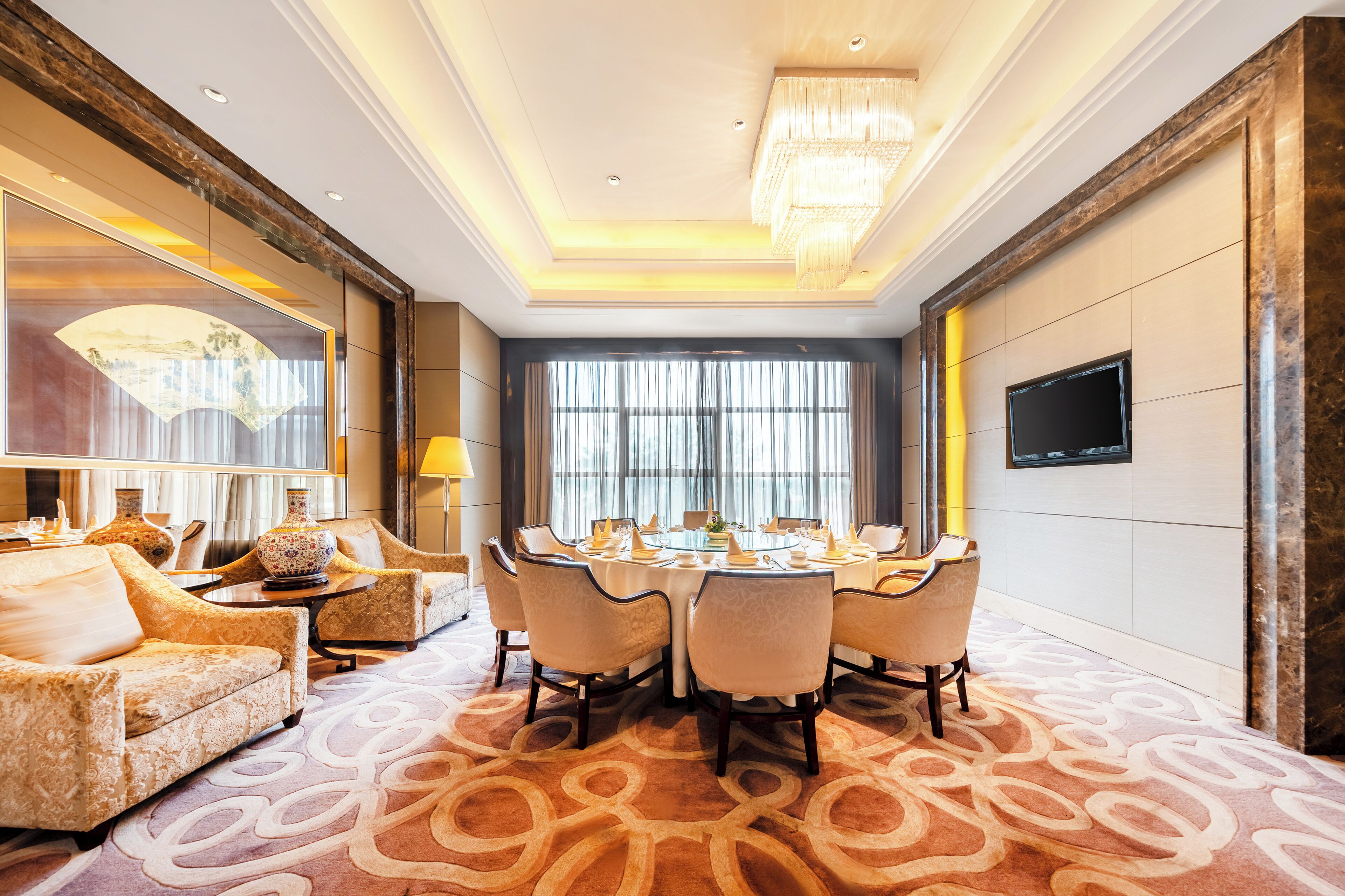 A dining area with a round table, chairs, and a chandelier.