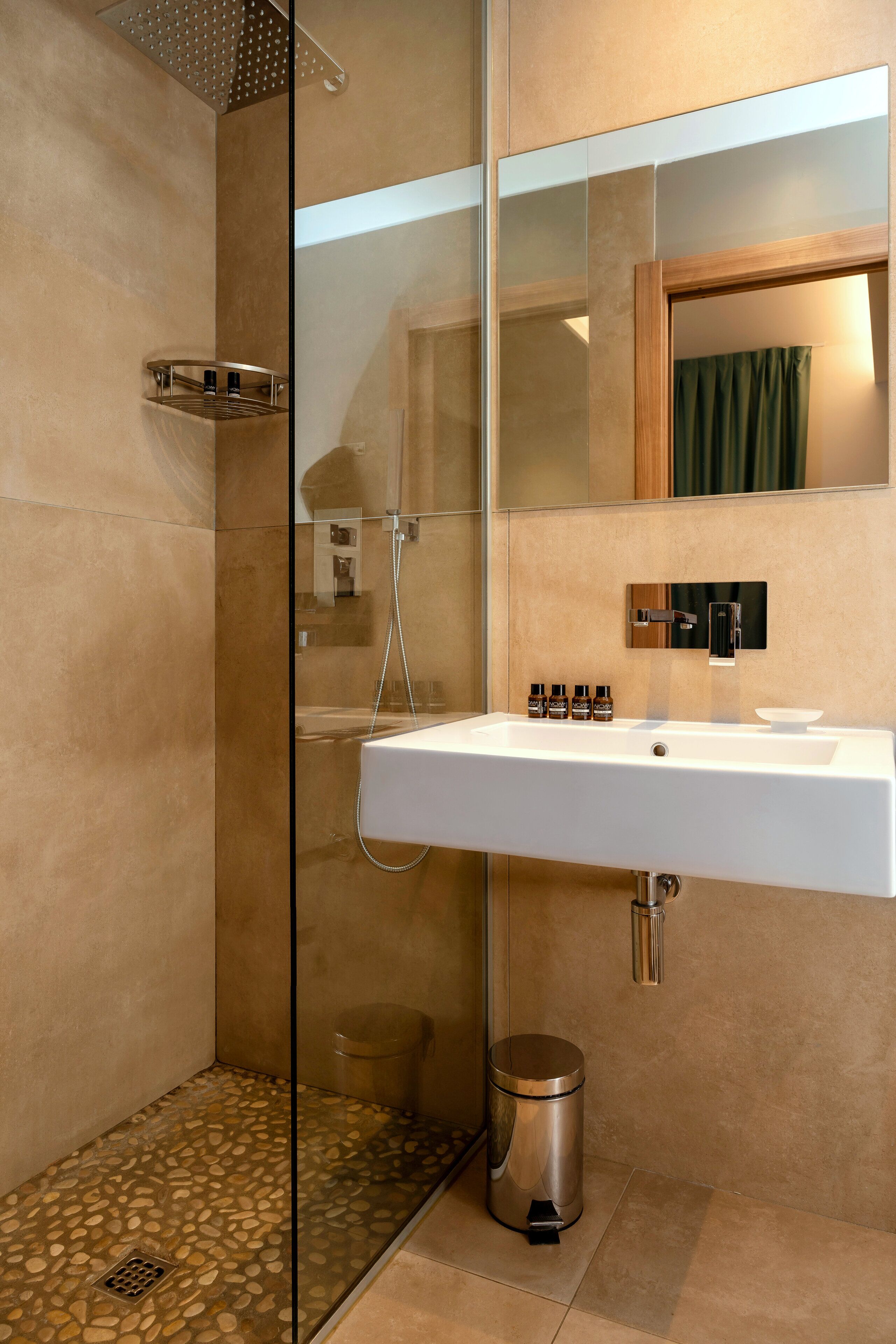 A modern bathroom with a glass-enclosed shower, a white sink, and a mirror above it.