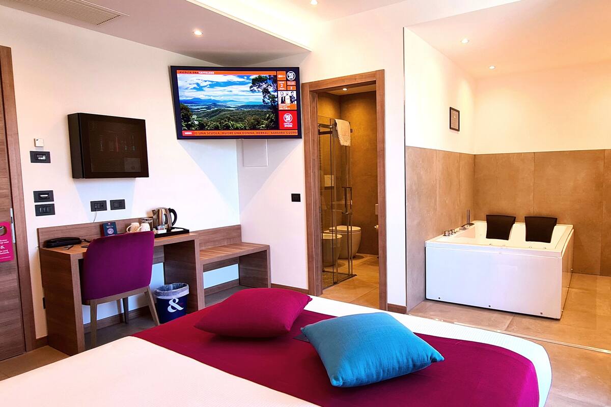Ein Hotelzimmer mit Bett, Schreibtisch, Fernseher, Duschbereich und Badezimmer.