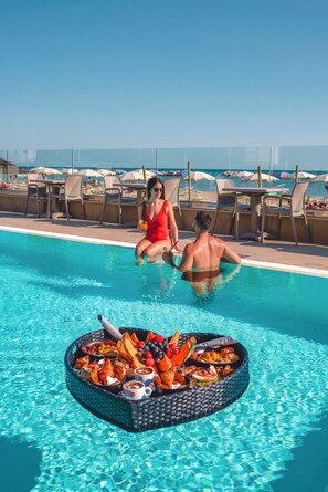 A poolside area with lounge chairs and a buffet table with food and drinks.