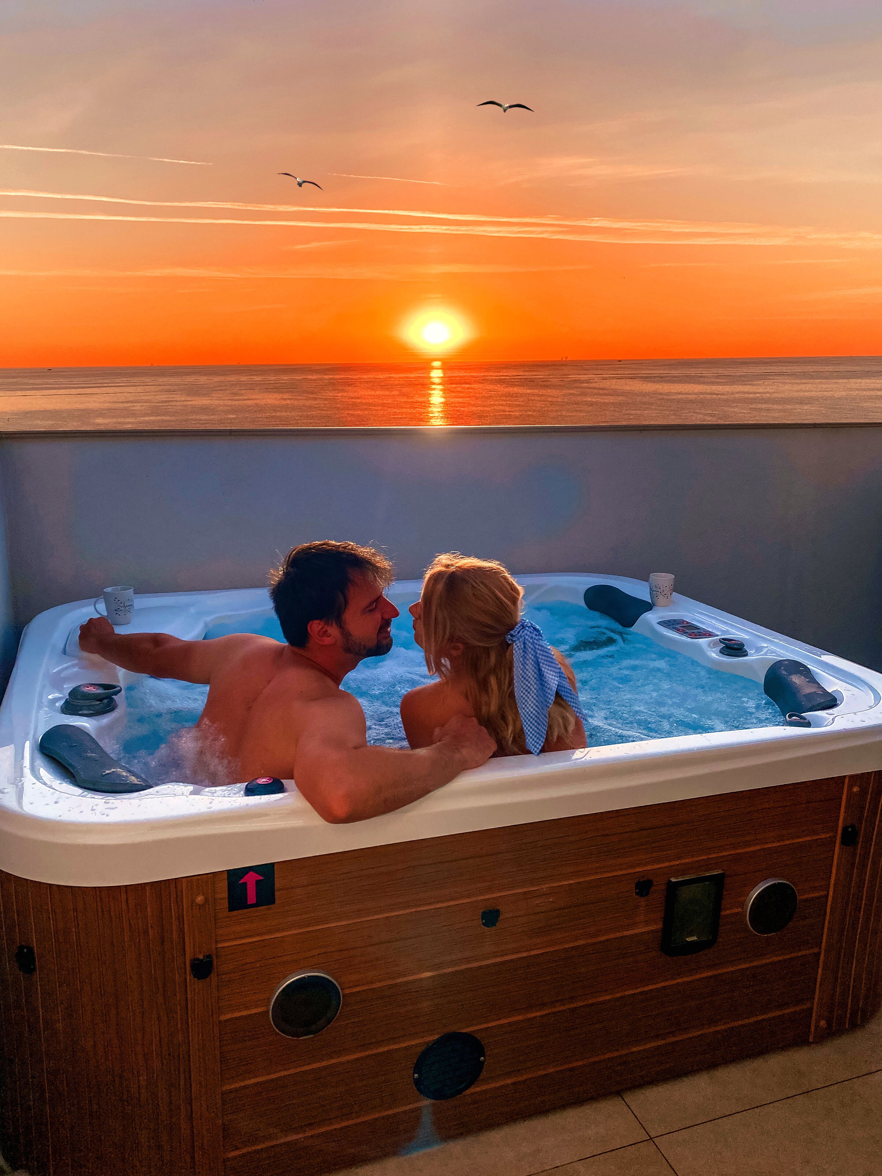Ein Paar entspannt in einer Whirlpool mit Blick auf den Sonnenuntergang.