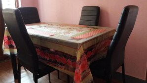 Une table à manger recouverte d’une nappe à motifs floraux, entourée de quatre chaises noires.
