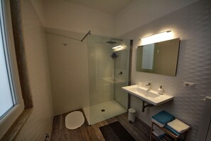 A modern bathroom with a glass-enclosed shower, a white sink, and a mirror above it. - Principe (Bari)