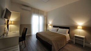 A hotel room with a bed, bedside tables, a TV, and a desk with a chair. - Principe (Bari)