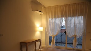 A room with a wooden bench, a lamp, and a window with curtains. - Principe (Bari)