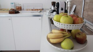 A kitchen counter with a fruit bowl containing apples, bananas, and pears. - Principe (Bari)