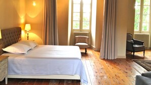 Un dormitorio con una cama grande, una silla, un escritorio y una ventana con cortinas.