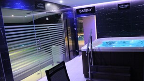 Ein moderner Poolbereich im Innenbereich mit Glaswand, Whirlpool und einem Schild mit der Aufschrift 'BASENY'.