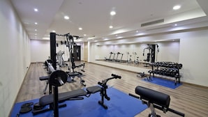 Ein Fitnessstudio mit verschiedenen Trainingsgeräten, darunter Laufbänder, Kraftgeräte und Kurzhanteln.