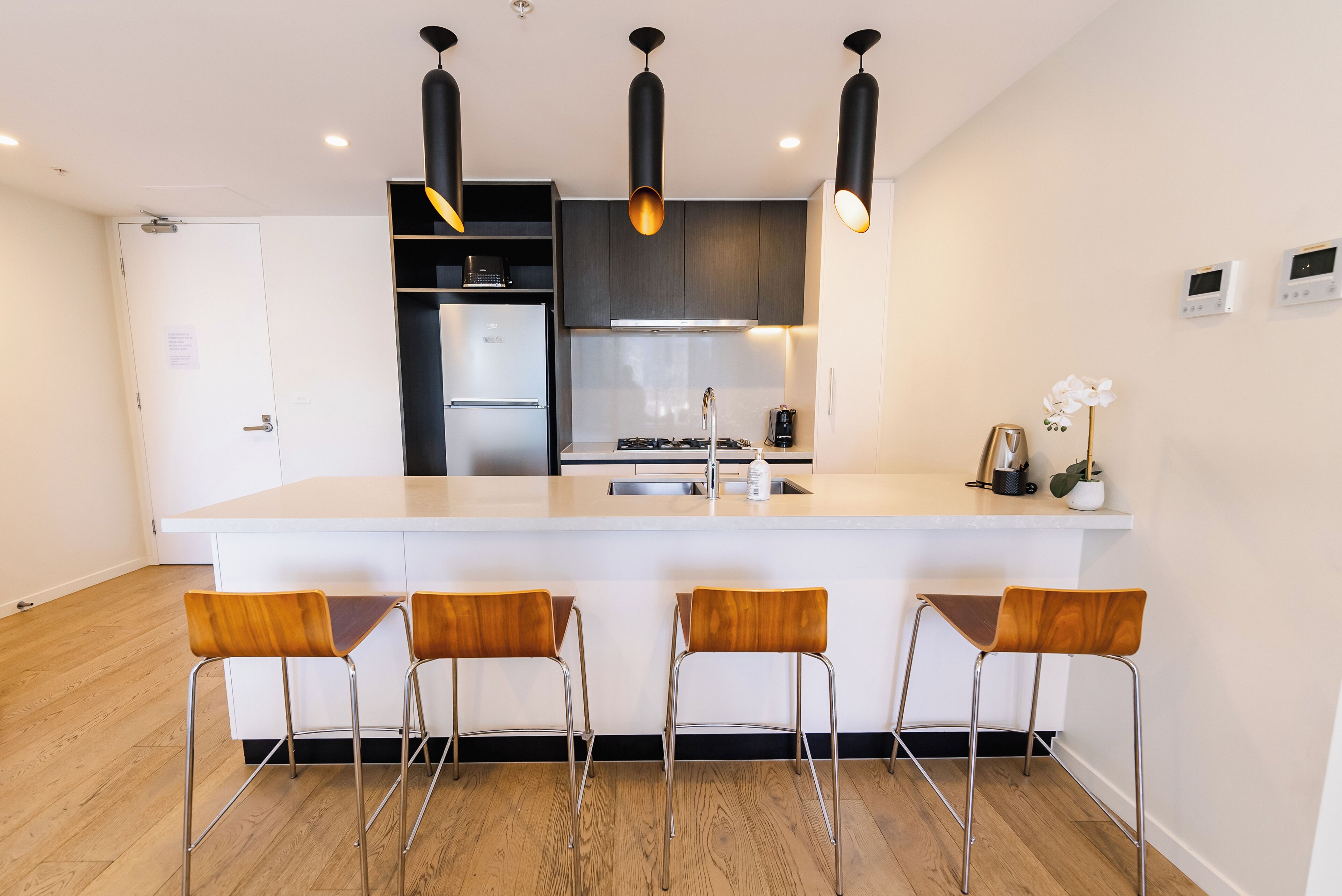 A modern kitchen with a central island, stainless steel appliances, and wooden chairs.