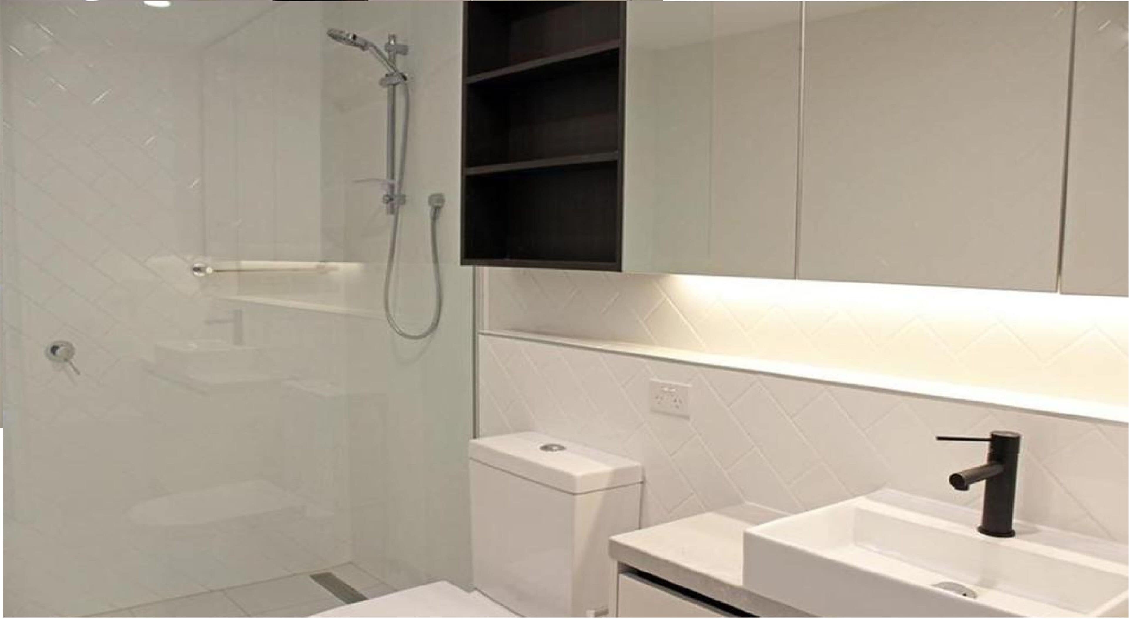 A modern bathroom with a shower, toilet, and sink.