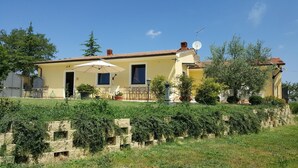 A two-story house with a patio, outdoor furniture, and a garden. - Agriturismo Podere Casa al Vento (Montepulciano)