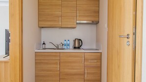 A compact kitchen with wooden cabinets, a stainless steel kettle, and a white countertop. - Imperiall Resort & MediSpa - Cottage (Ustronie Morskie)