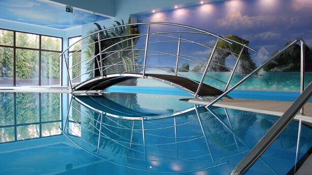 An indoor swimming pool with a glass barrier and a mural of a tropical landscape. - Imperiall Resort & MediSpa - Cottage (Ustronie Morskie)