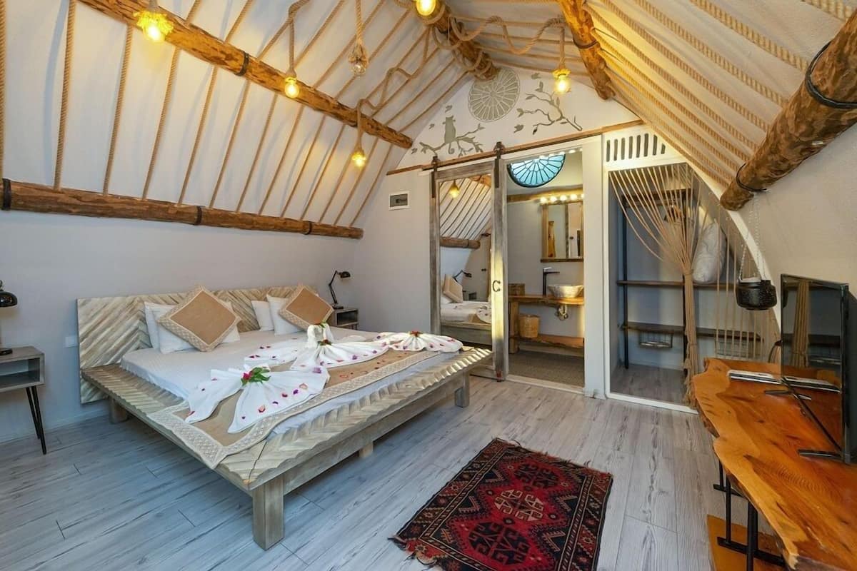 A cozy bedroom with a wooden bed, a mirror, and a view of a balcony.