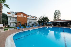 A hotel with a swimming pool, lounge chairs, and a sign reading "IKSIRCH BABA HOTEL". - Iksirci Baba Hotel (Fethiye)