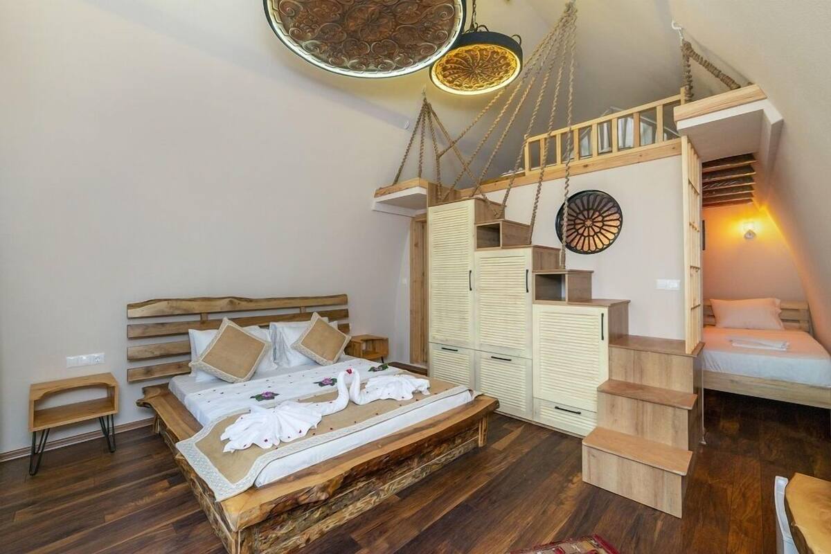 A bedroom with a wooden bed, a wardrobe, a small table, and a hanging light fixture.