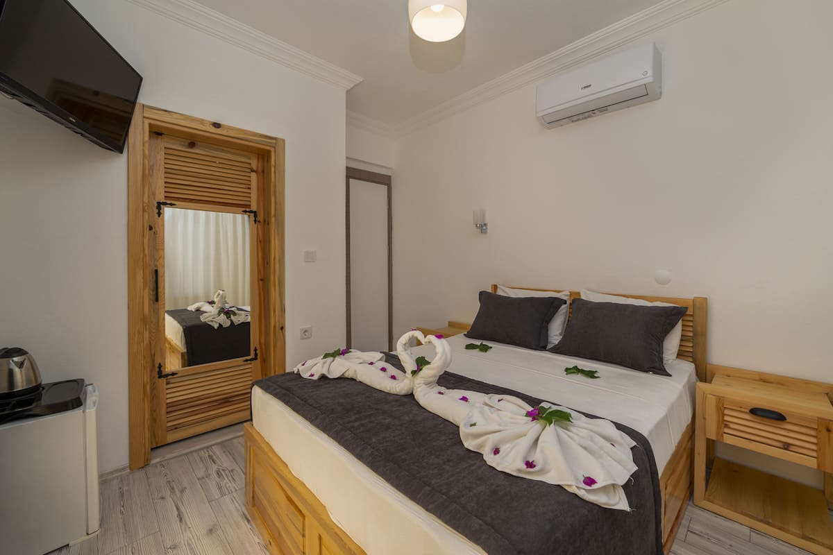 A bedroom with a bed, wooden headboard, bedside table, and a mirror.