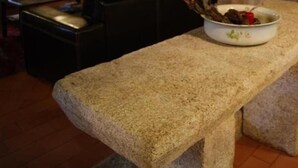 A stone bench in a rustic room with a television and a lamp. - Casa d'Acha (Idanha-a-Nova)