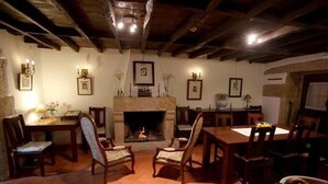 A cozy room with a fireplace, wooden furniture, and framed pictures on the walls. - Casa d'Acha (Idanha-a-Nova)