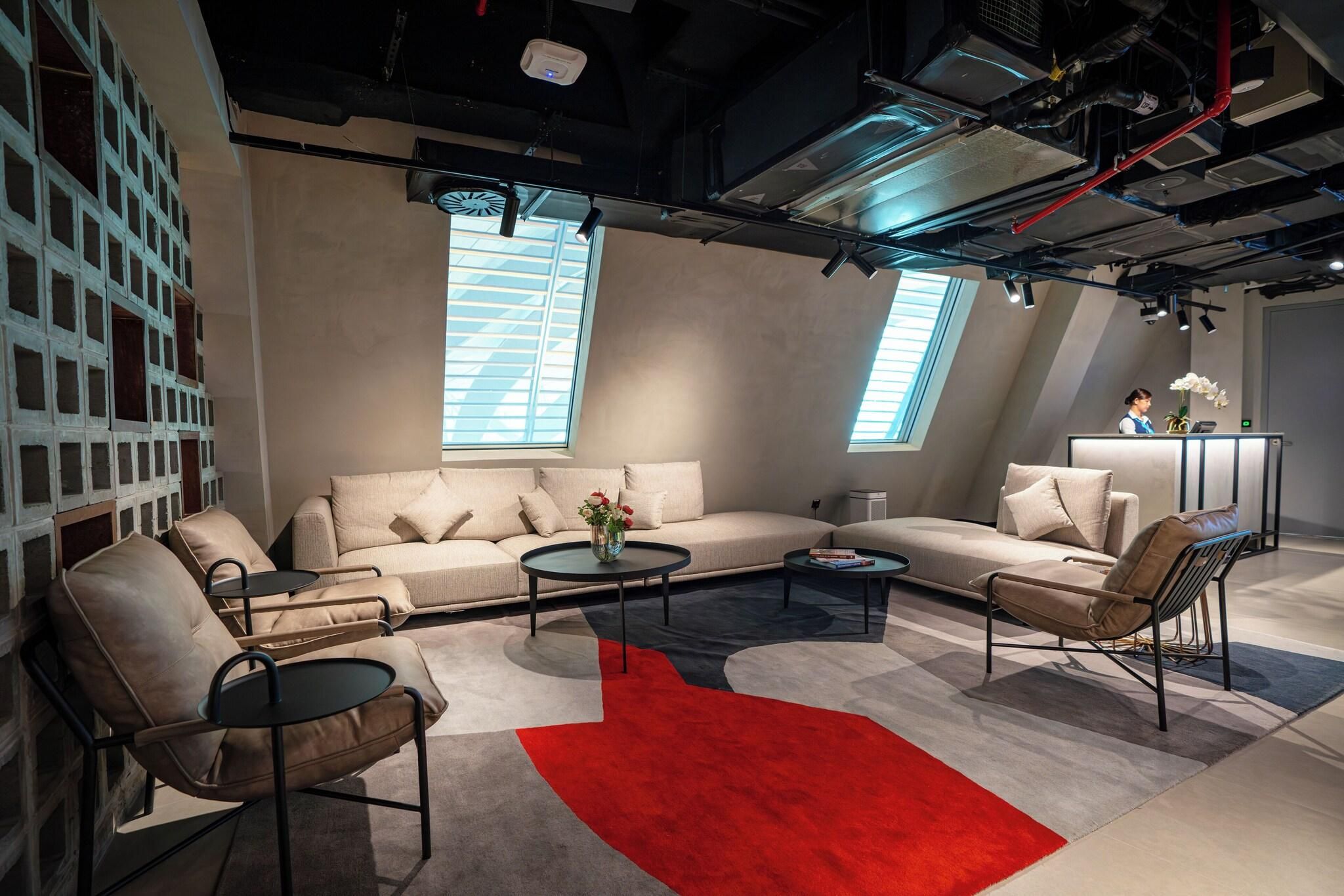 Un intérieur moderne avec un canapé, des fauteuils, une table basse et un tapis rouge.