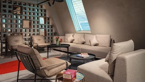 Ein modernes Wohnzimmer mit einer Couch, Sesseln, einem Couchtisch und einem Bücherregal.