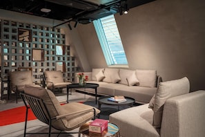 A modern living room with a sofa, armchairs, a coffee table, and a bookshelf. - Premier Inn Abu Dhabi Airport Hotel (Abu Dhabi)