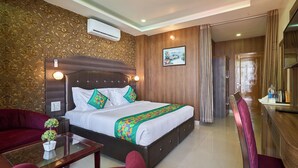 A hotel room with a large bed, a sofa, a dining table, and a TV. - Treebo Roshan House With Valley View (Dharamshala)