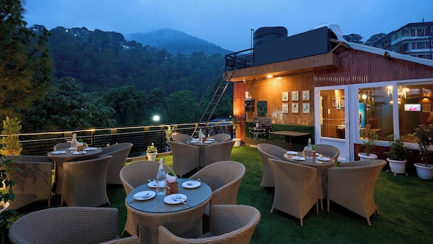 An outdoor dining area with wicker furniture and a view of a mountain. - Treebo Roshan House With Valley View (Dharamshala)