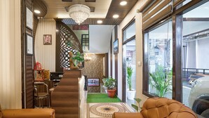 A reception area with a staircase, seating, and a reception desk. - Treebo Roshan House With Valley View (Dharamshala)