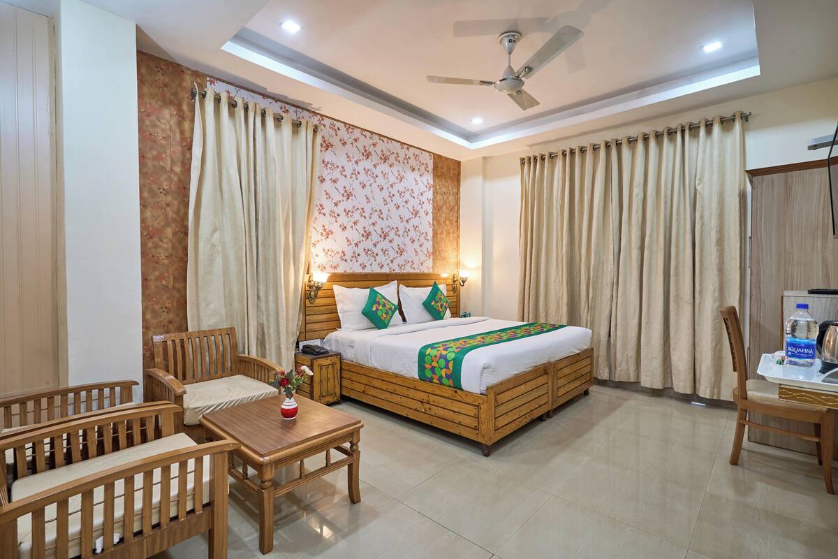 A hotel room with a bed, wooden furniture, a ceiling fan, and curtains.