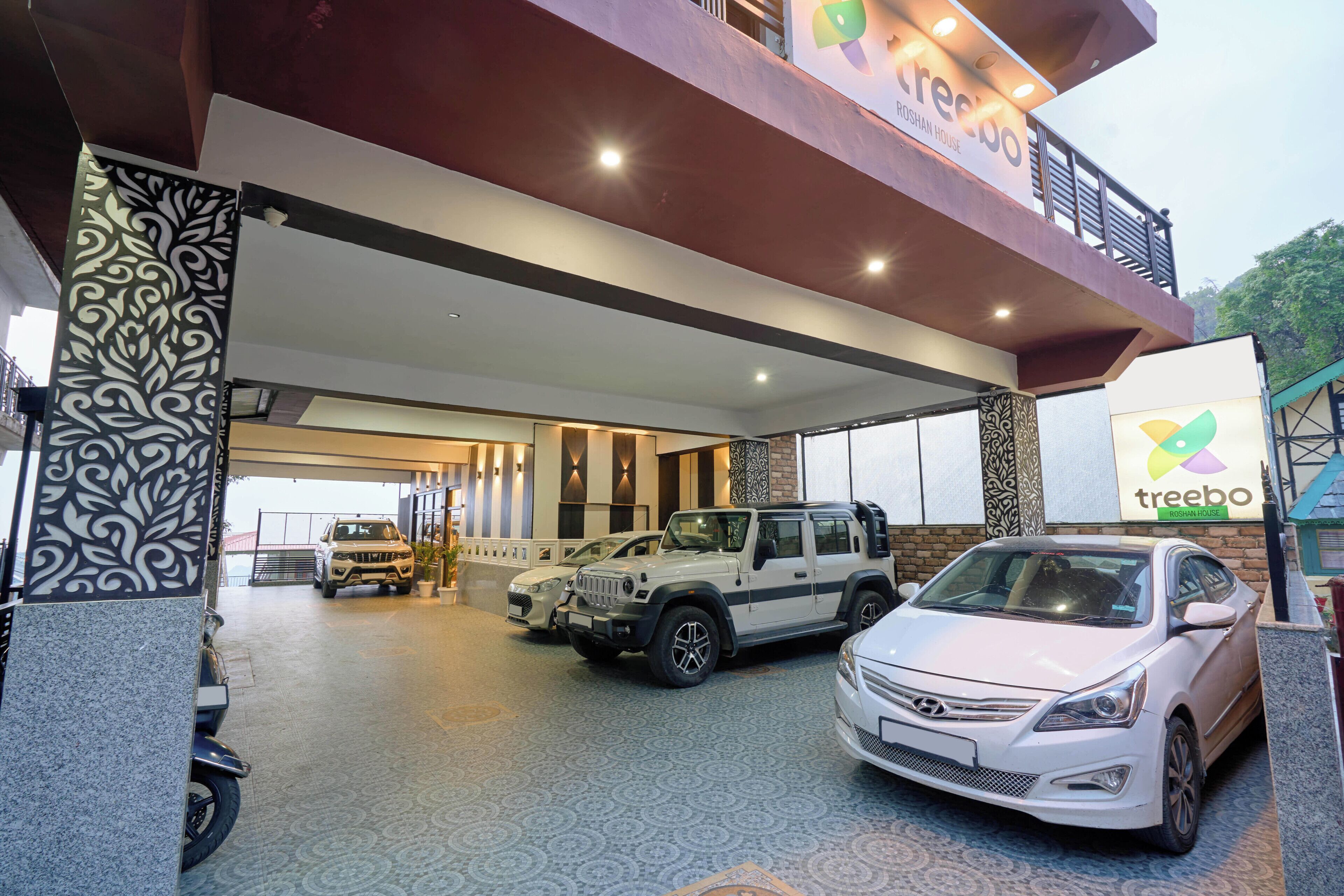 A car dealership with multiple vehicles on display, including SUVs and sedans, under a covered area with a modern architectural design.