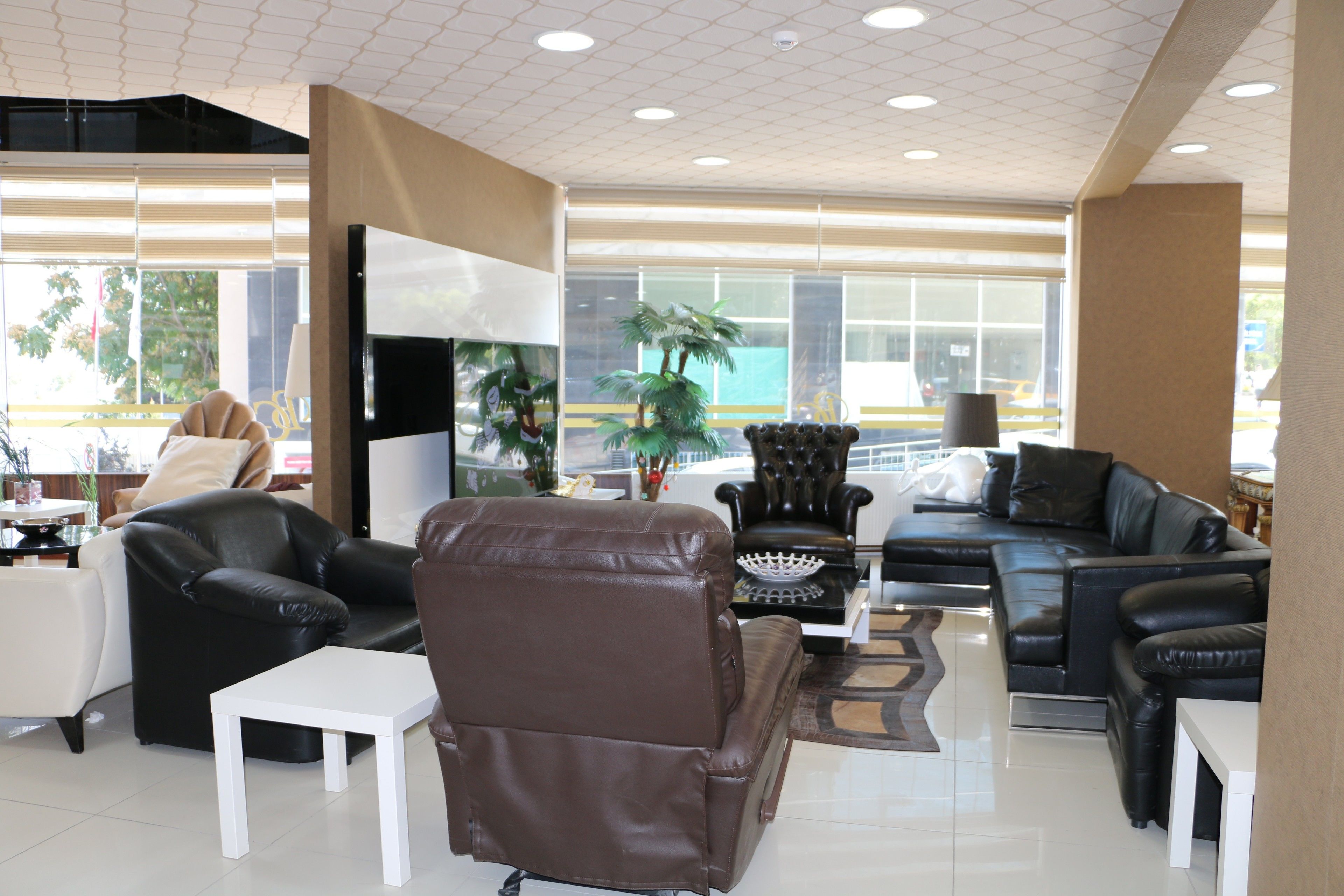 Un salón amplio con sofás de cuero, una mesa de centro blanca y un televisor de pantalla plana grande.
