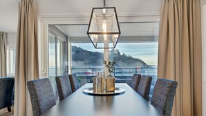 A dining area with a long table, six chairs, and a hanging light fixture. - Wright Apartments (Oslo)