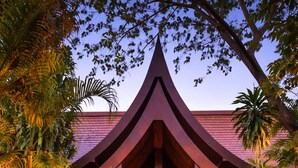 Um edifício com um telhado característico, porta frontal e um jardim bem cuidado.