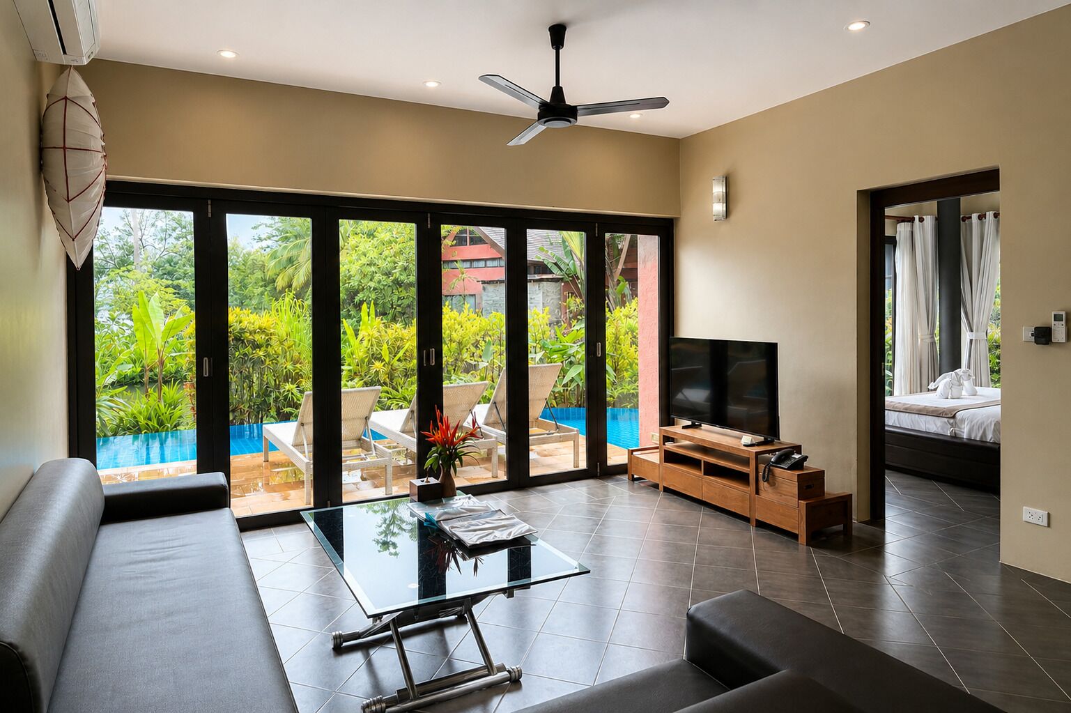 A modern living room with a glass coffee table, a flat-screen TV, and a sofa.