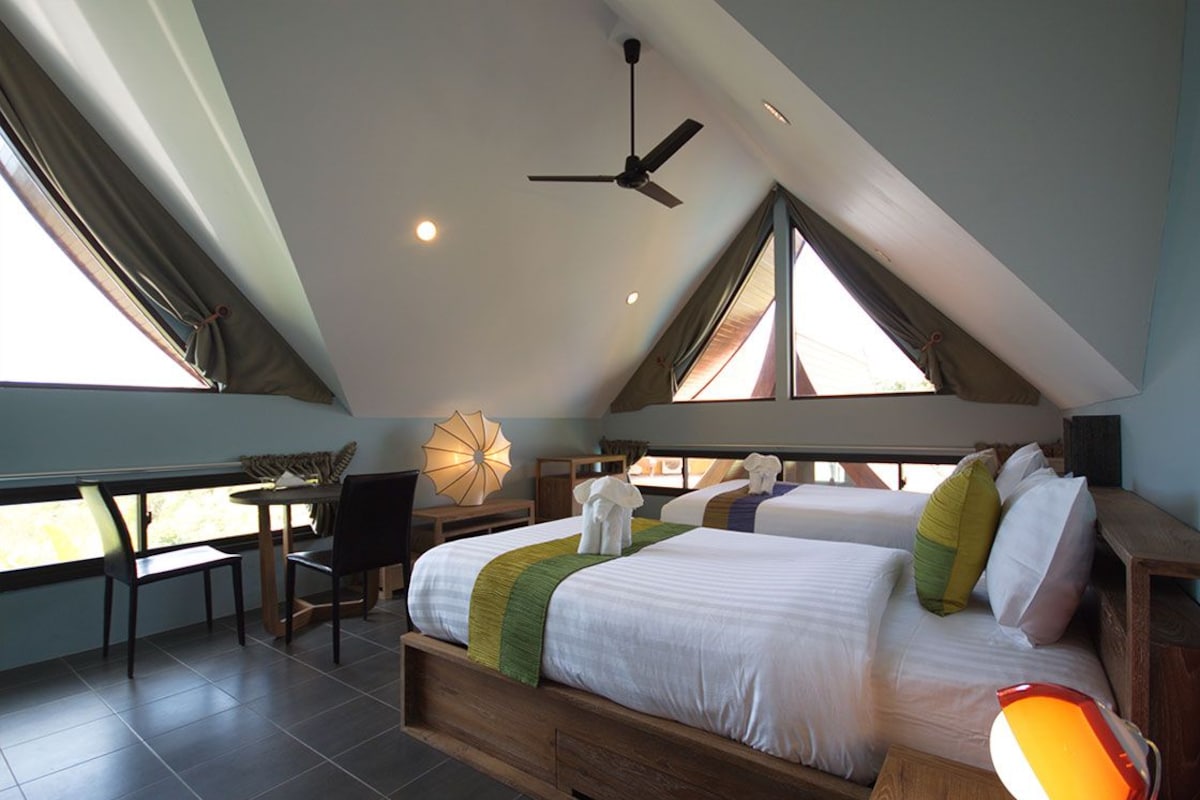 A bedroom with two beds, a desk, and a chair.