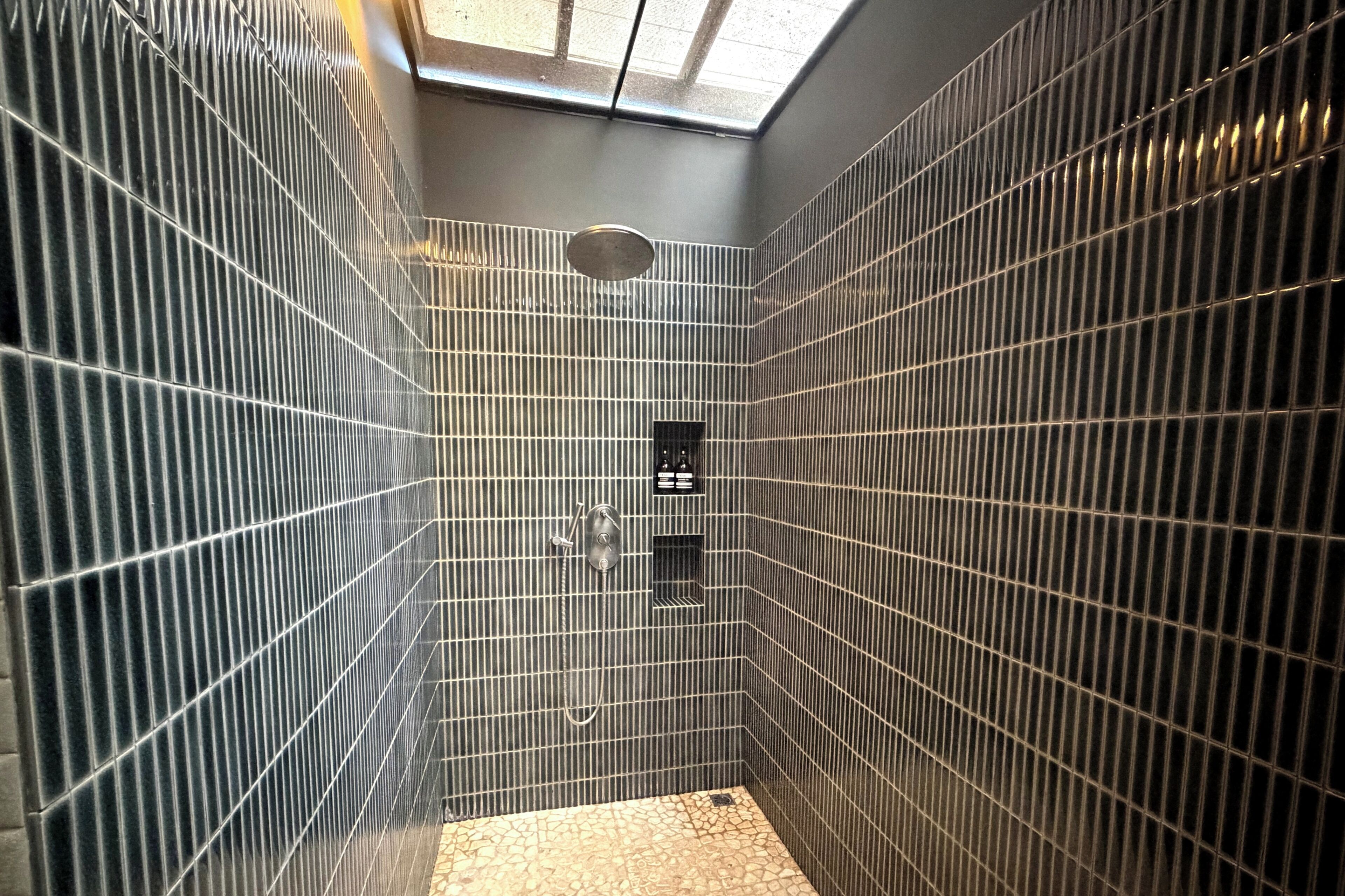 Un baño pequeño con azulejos, un tragaluz, ducha y retrete.