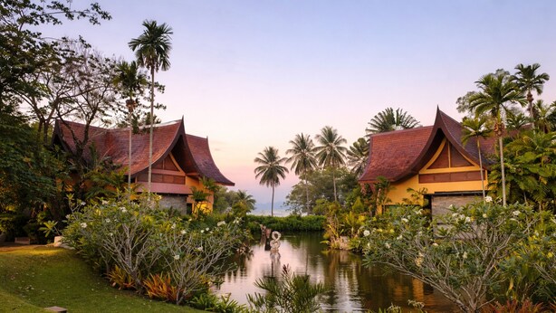 Um resort com várias construções, um lago e vegetação exuberante.