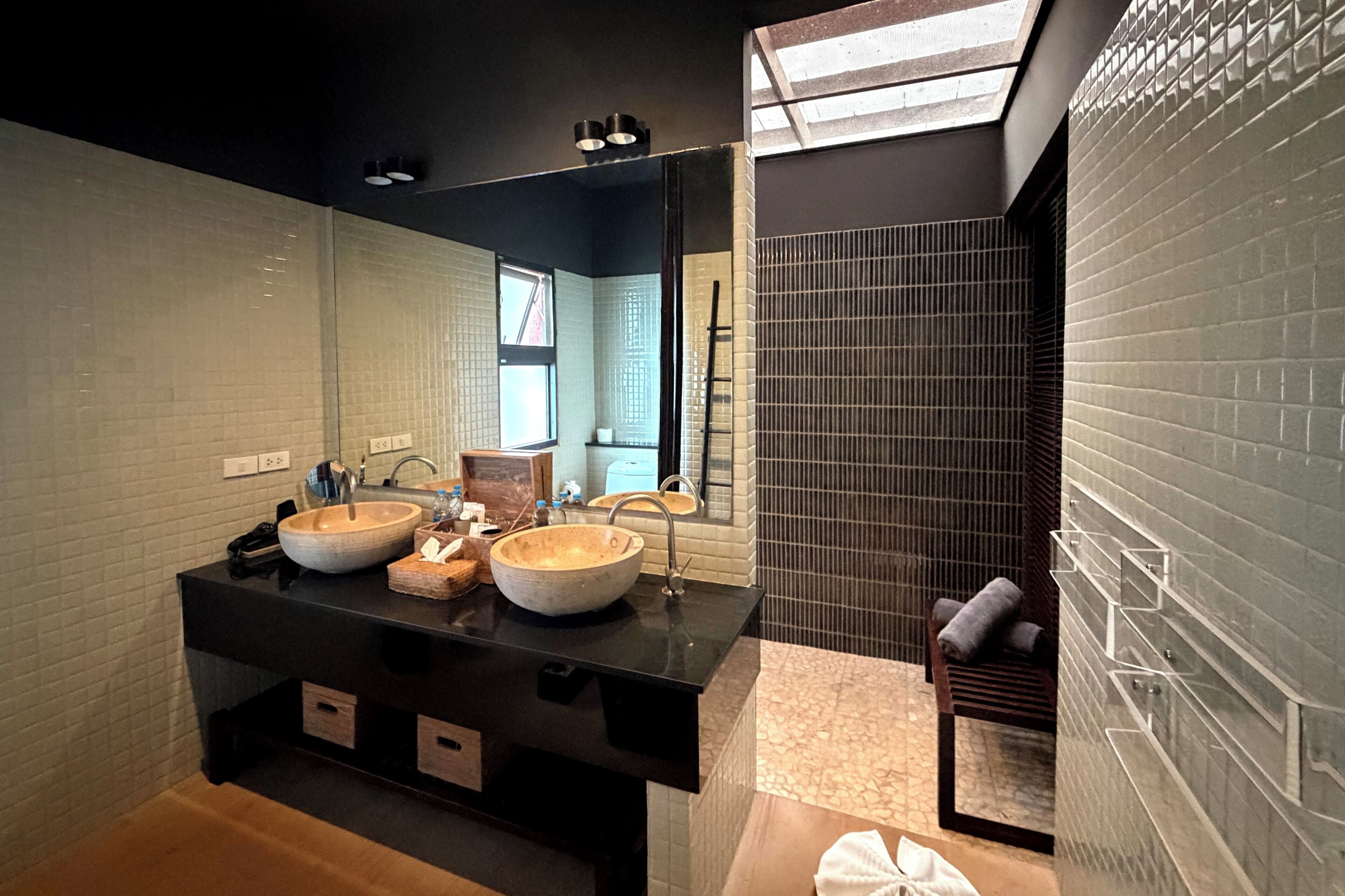 A modern bathroom with a black vanity, two sinks, and a large mirror.