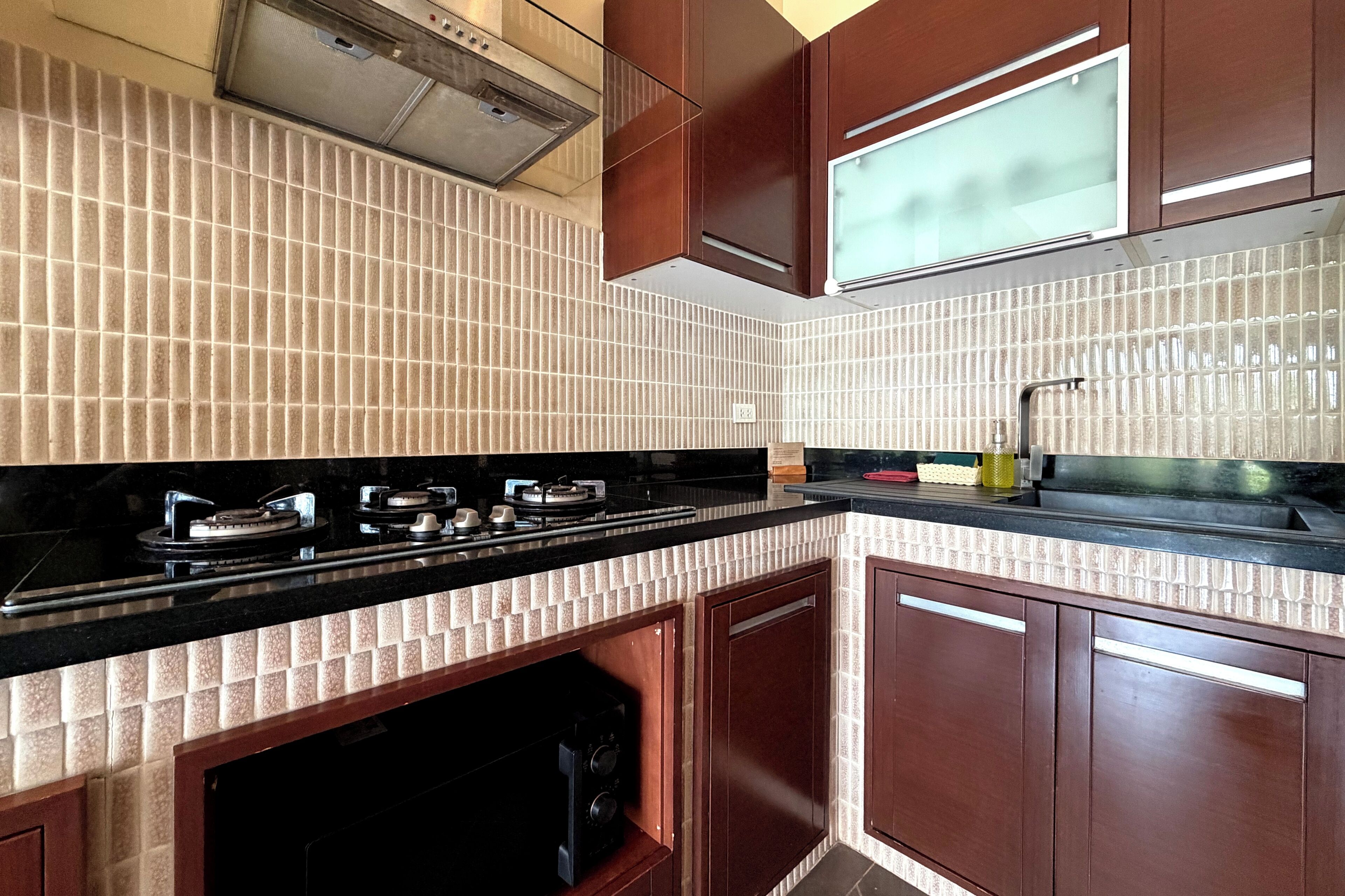 A kitchen with a black countertop, a gas stove, a sink, and wooden cabinets.
