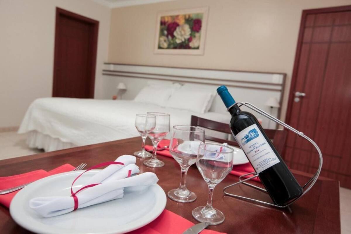 Una mesa de comedor bien puesta con una botella de vino, copas y platos en una habitación de hotel.