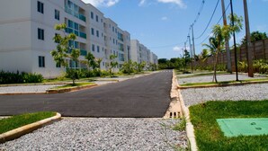 A multi-story residential building with a paved road in front, surrounded by greenery and palm trees. - Hotel Dom Baroni (Guarapuava)