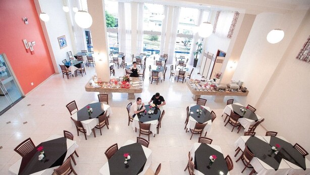 A spacious dining area with multiple tables and chairs, large windows, and a bright atmosphere. - Hotel Dom Baroni (Guarapuava)