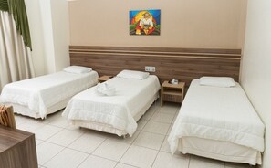 Hotelkamer met drie enkele bedden, een houten hoofdbord, een schilderij aan de muur en een nachtkastje met een telefoon.