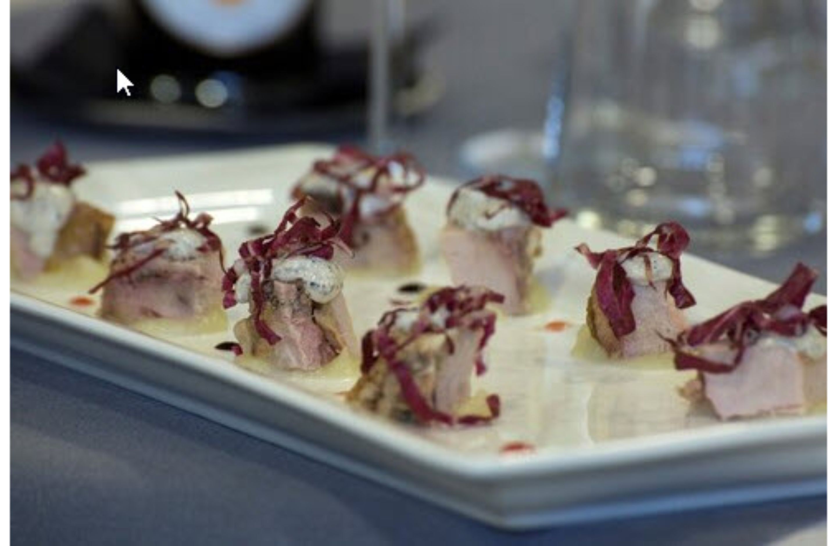 Un plato rectangular blanco con varios alimentos, cada uno decorado con un adorno rojo.