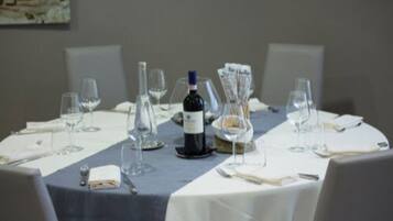 Una mesa de comedor preparada con copas de vino, una botella y un menú.