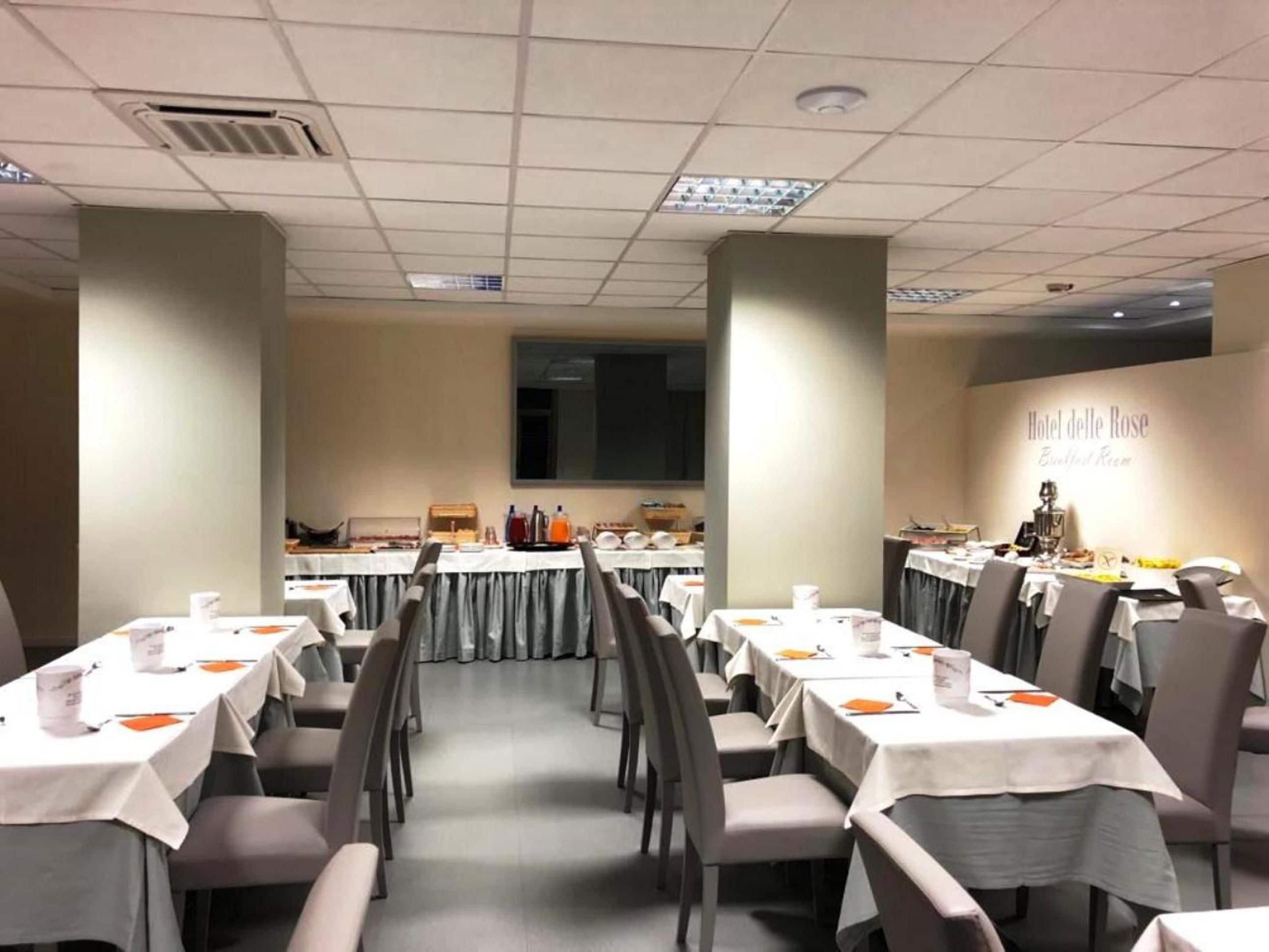 Un salón de conferencias con varias mesas, sillas y una pantalla grande.