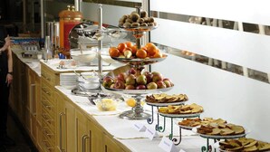 Un bufé con diversas opciones de comida, incluyendo frutas, pasteles y pan.